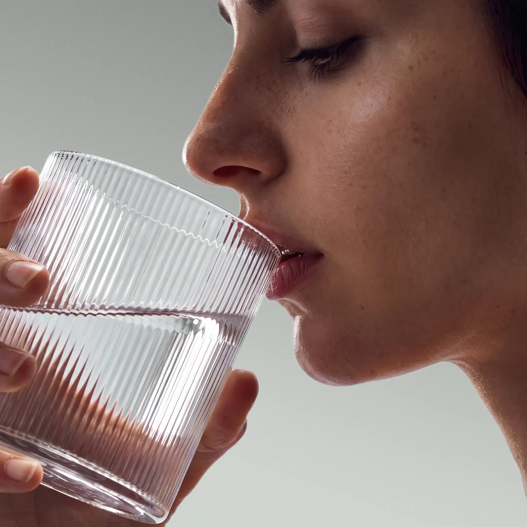 bevendo il collagene in polvere di Aldous sciolto in un bicchiere d'acqua