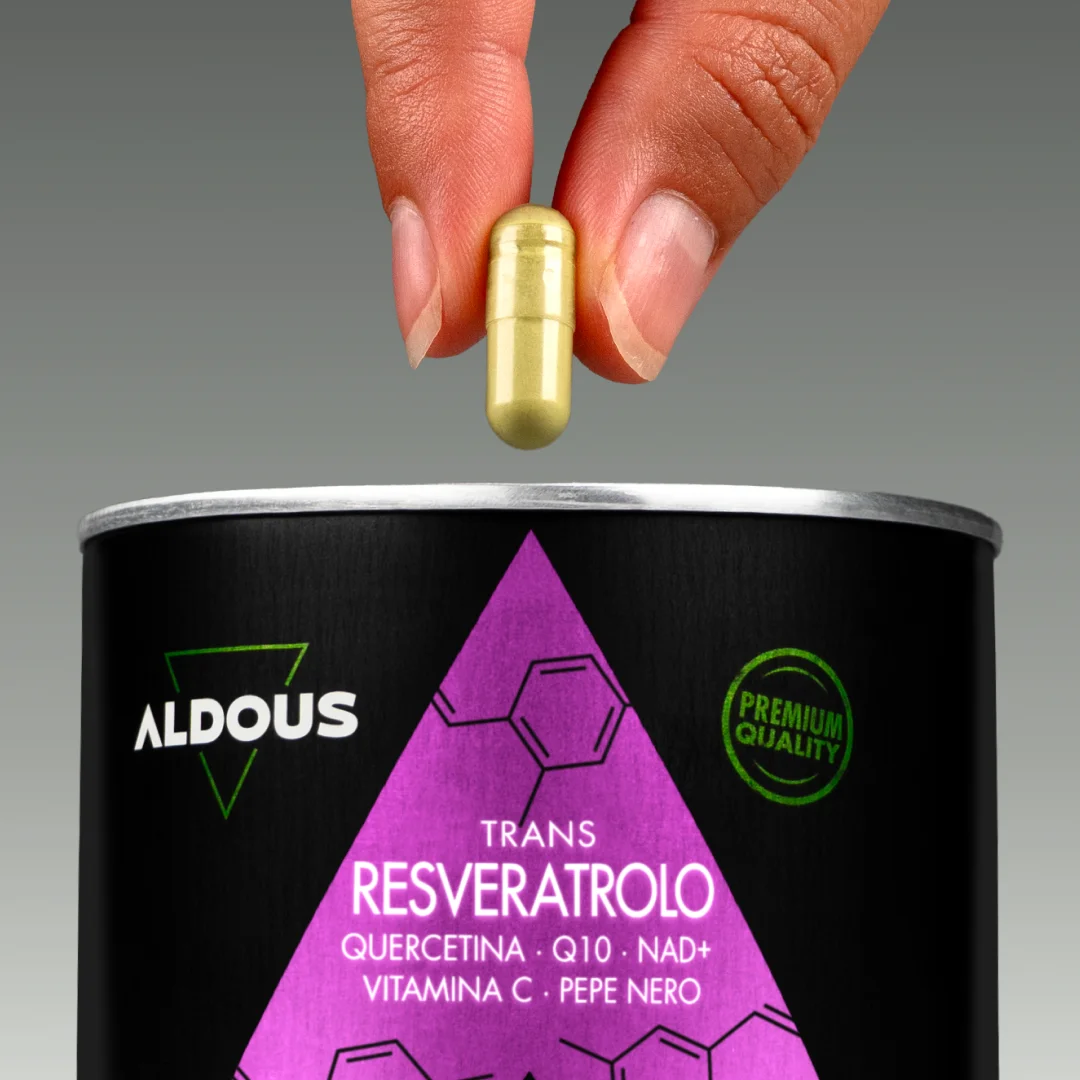 Mano che tiene una capsula sopra il barattolo di Resveratrolo Aldous con quer...
