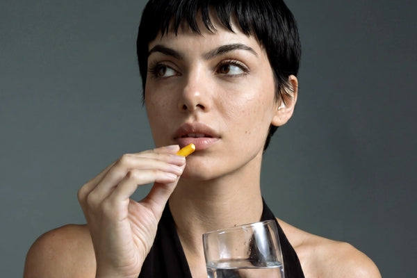 Immagine di una donna che tiene in mano una capsula di Curcuma Aldous.